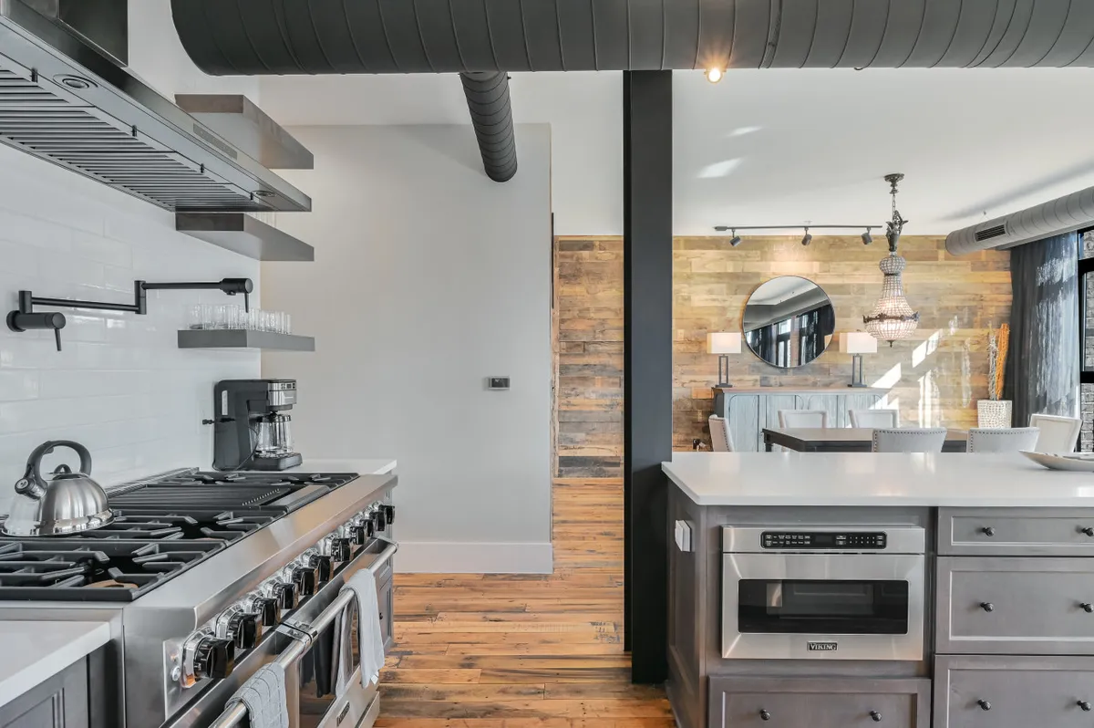 A welcoming kitchen and dining space with stainless steel appliances, wooden countertops, and a cozy dining area under a glowing chandelier. The inviting setup is ideal for evening entertaining or sharing a meal before a night out in the city.