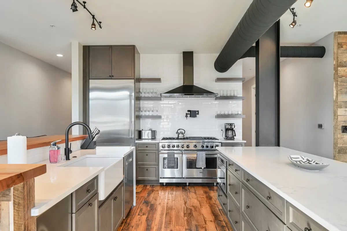 A spacious kitchen with a large island, stainless steel appliances, open shelving, and inviting wooden accents. The scene suggests an atmosphere ideal for hosting dinner parties, holiday baking, and casual breakfasts, evoking both functionality and warmth.